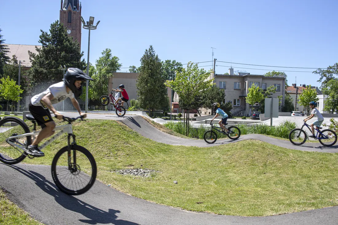 Rowerzyści na pumptracku w Ostrzeszowie, w tle kościół